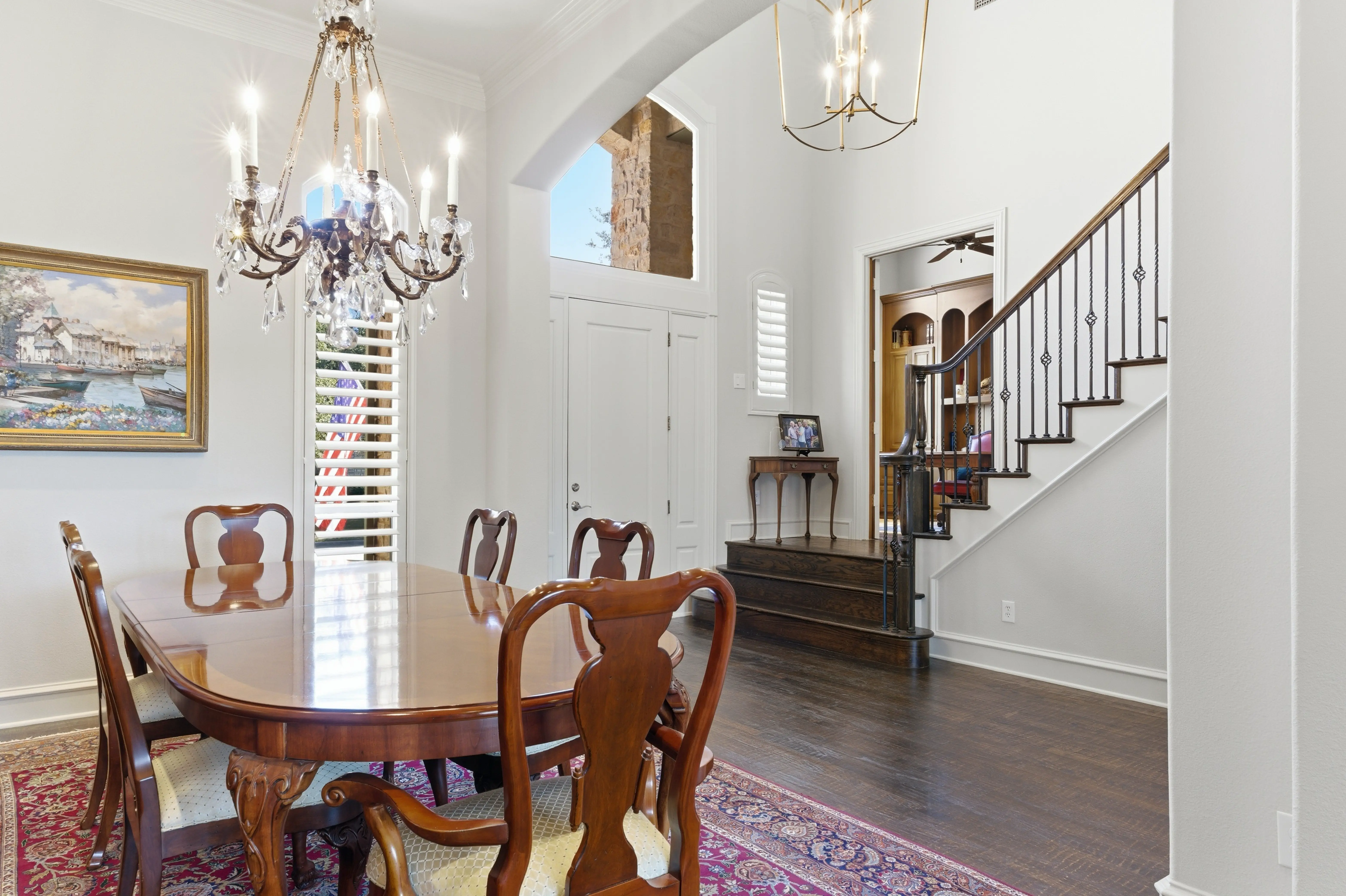 Dining area with crystal chandelier, architectural archway to front entry and staircase